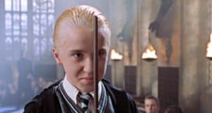 Tom Felton as Draco Malfoy holding his wand in front of his face