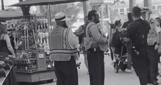 Disneyland Resort security talks to a drunk guest at Disney California Adventure Park. Image is in black and white.