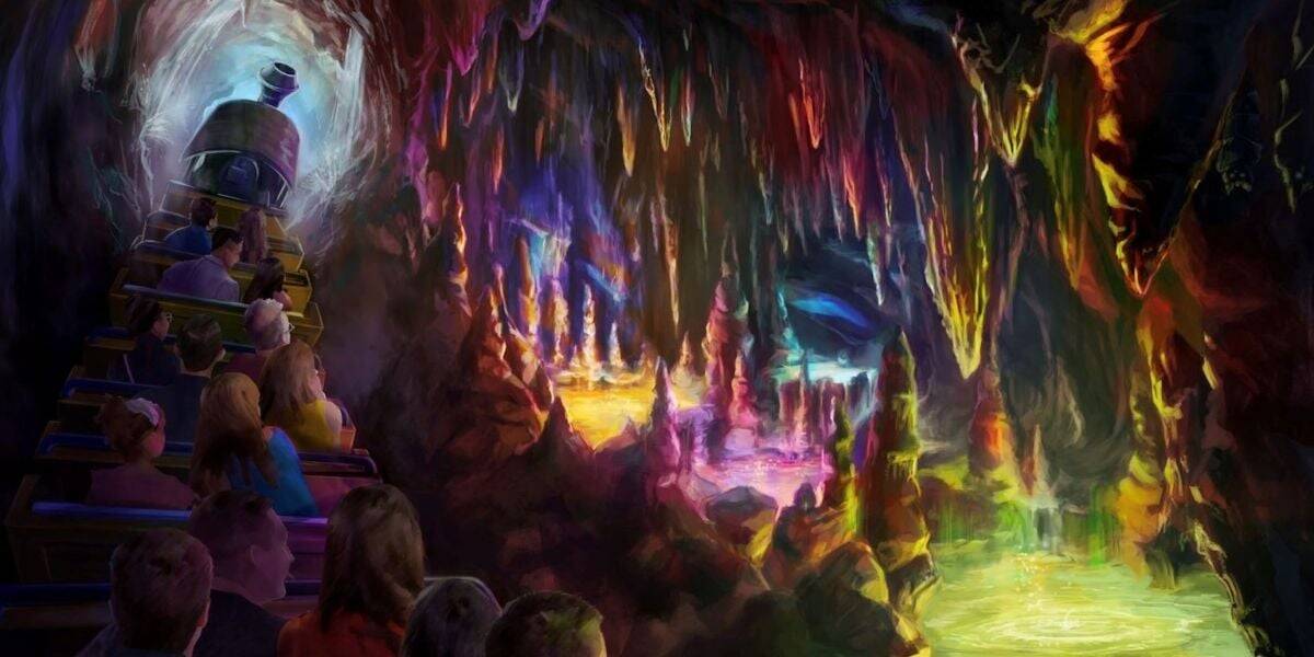 A group of people rides a train through a colorful, glowing cave filled with vibrant stalactites and stalagmites, illuminated by multicolored lights and reflections in luminous pools of water.
