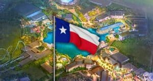 An illustrated aerial view of an amusement park with a large Texas state flag prominently displayed in the foreground. The park features rides, buildings, and a central water area, all brightly lit at night.