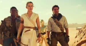Three people dressed in sci-fi adventure clothing stand confidently in a desert, with a gold humanoid robot and spaceship in the background under a bright sky.
