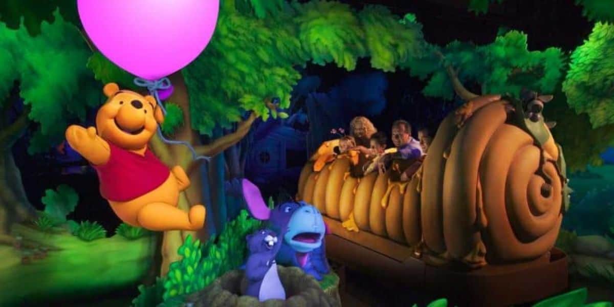Winnie the Pooh floats with a pink balloon near guests on the beehive-themed ride at the park, now as a public domain icon.