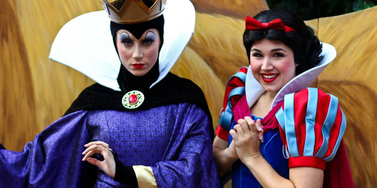 The Evil Queen and Snow White greet guests together at a Disney park, capturing the magic of the beloved fairy tale.