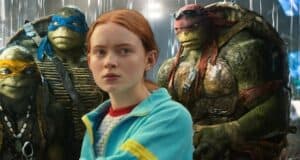 Sadie Sink as April O’Neil poses with the Teenage Mutant Ninja Turtles in moody lighting, teasing the Ninja Turtles Reboot.