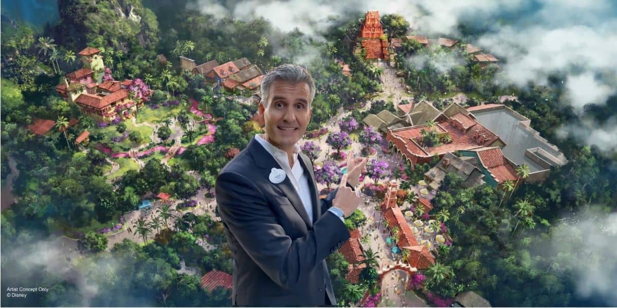 A park ambassador in a sharp suit happily welcomes guests, pointing out must-see attractions on a vibrant map at Universal Studios.