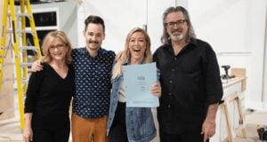 Cast members in a Disney Parks backstage area smile together, one holding a script, embodying friendly teamwork and behind-the-scenes magic.