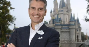 Sharp-dressed guest beams in front of a storybook castle at Disneyland, ready for a magical day of adventure and fun.