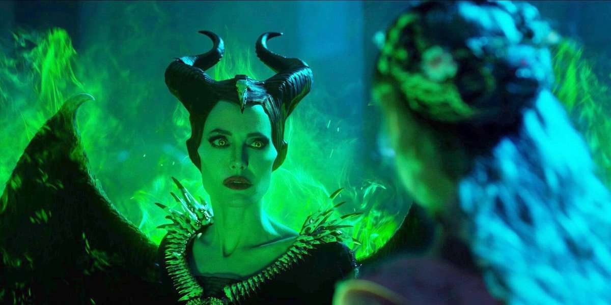 Maleficent, with her iconic horns and glowing green wings, locks eyes with a guest, surrounded by dramatic green flames.