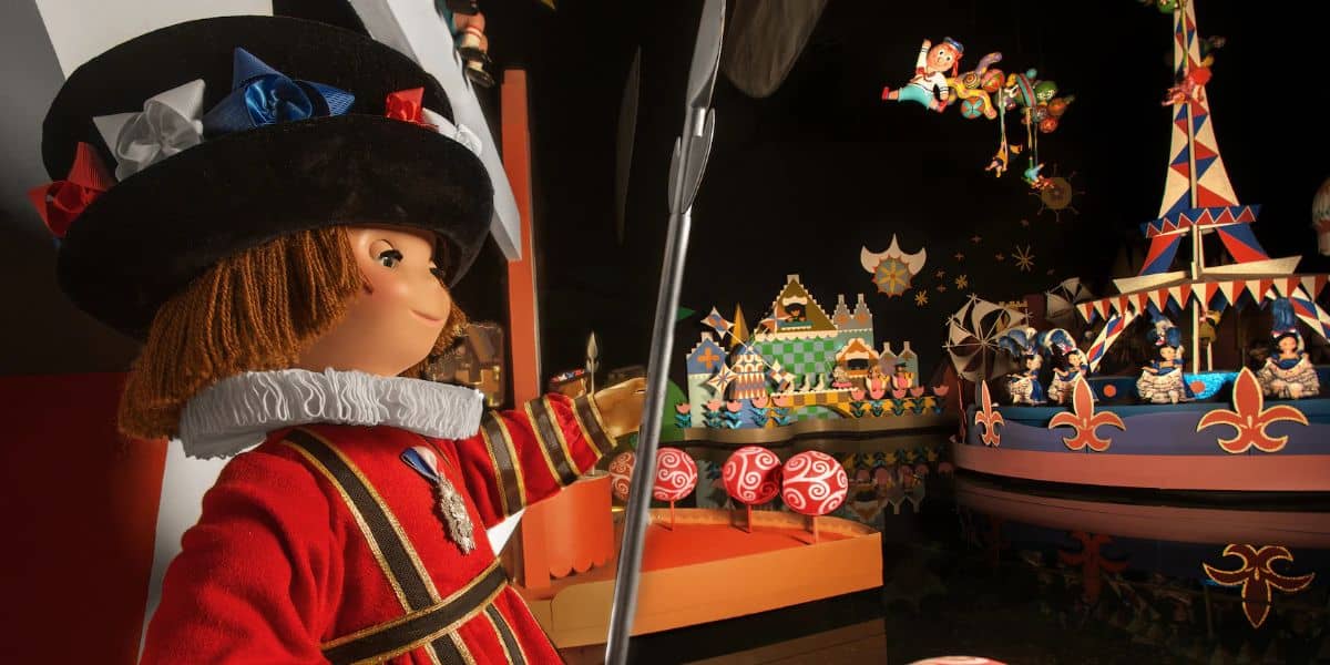 An It’s a Small World character doll in vibrant traditional attire greets guests inside the ride’s playful, carnival-inspired setting.