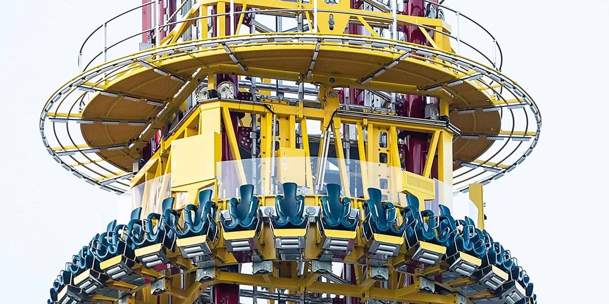 Orlando’s iconic yellow and blue drop tower beckons thrill-seekers, its empty seats bold against a bright white sky.