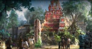 Visitors snap photos of a vivid red temple ruin set in a jungle, part of an ancient adventure zone amid lush trees and stone relics.