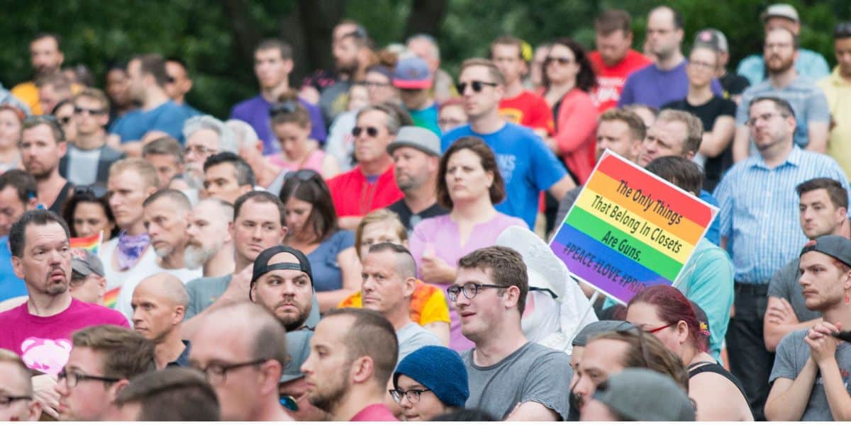 A rally crowd; one attendee’s rainbow sign links Disney World and LGBTQ+ rights, recalling the Pulse tragedy 10 years ago.