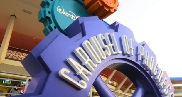 Vibrant Carousel of Progress sign at Disney World, shaped like blue gears, celebrating Walt Disney’s classic attraction.