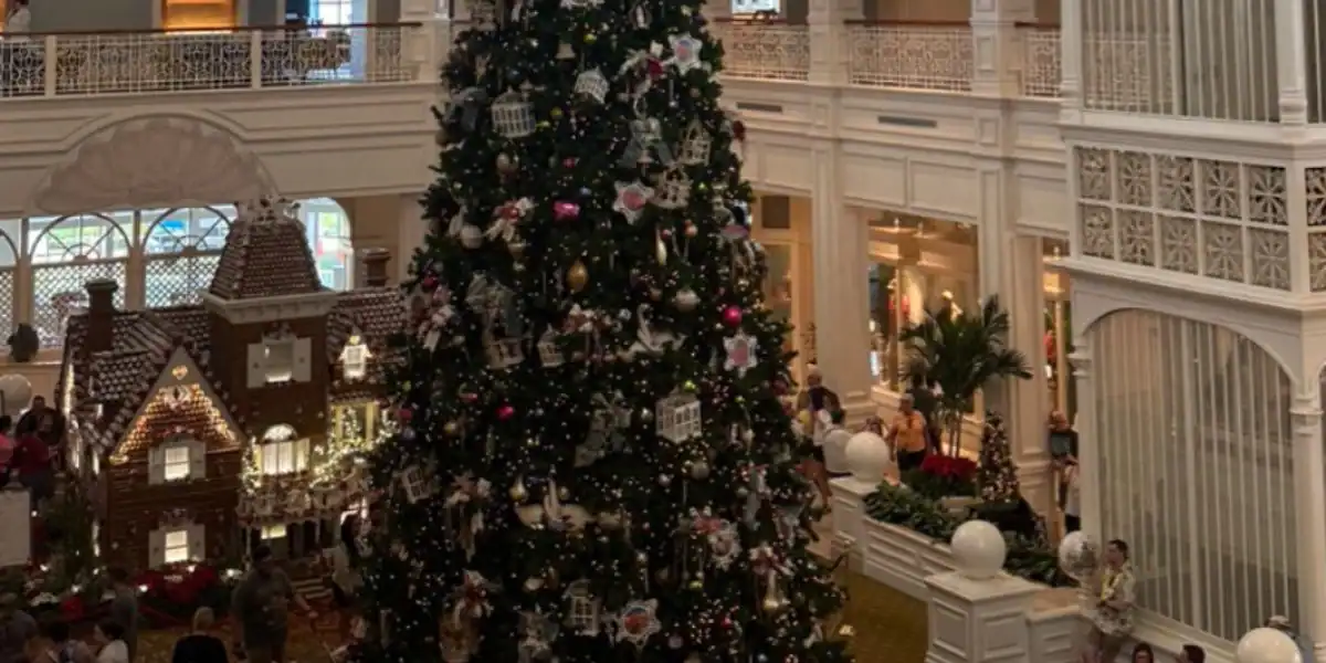 Towering Christmas tree adorned with ornaments in a lavish resort lobby, surrounded by Disney holiday decor and magic.