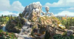 Radiator Springs racers zip along a winding mountain road at Cars Land, surrounded by cascading waterfalls, lush trees, and the iconic Cadillac Range rock formation shaped like classic cars.