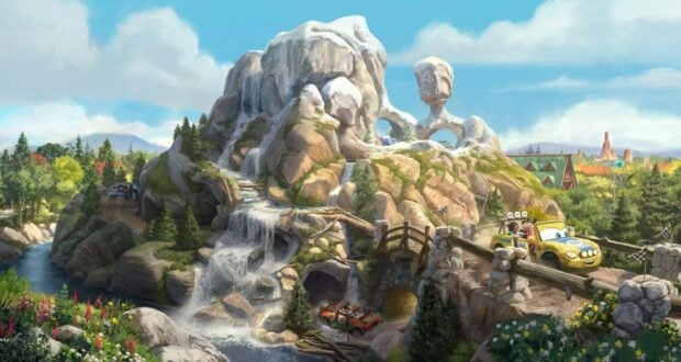 Radiator Springs racers zip along a winding mountain road at Cars Land, surrounded by cascading waterfalls, lush trees, and the iconic Cadillac Range rock formation shaped like classic cars.