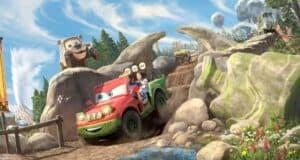 Guests delight as they zoom along a muddy, rocky track in a cheerful, cartoon-style car at the amusement park, surrounded by playful scenery with trees, boulders, and other riders’ cars.