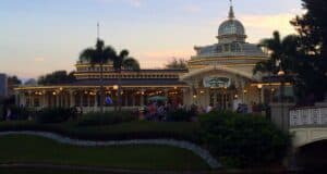 Elegant Victorian-themed restaurant with a stunning glass dome centerpiece, sparkling under enchanting string lights, nestled amid swaying palm trees as vibrant sunset hues set the perfect backdrop for an unforgettable evening at the park.