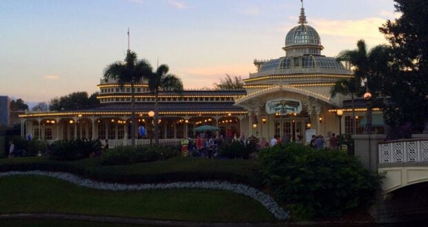Elegant Victorian-themed restaurant with a stunning glass dome centerpiece, sparkling under enchanting string lights, nestled amid swaying palm trees as vibrant sunset hues set the perfect backdrop for an unforgettable evening at the park.