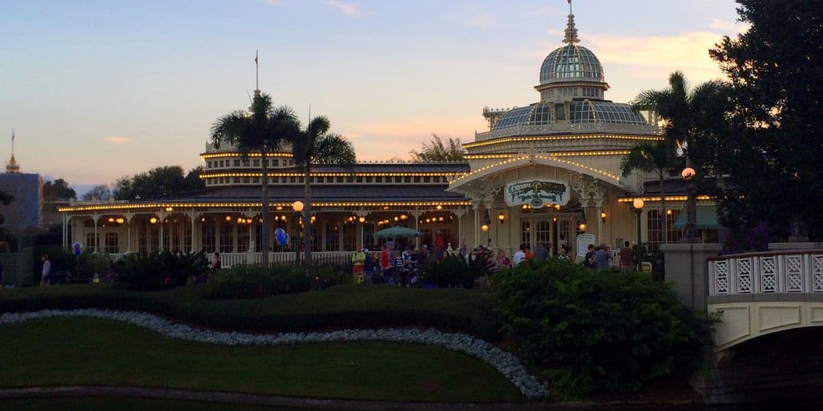 Elegant Victorian-themed restaurant with a stunning glass dome centerpiece, sparkling under enchanting string lights, nestled amid swaying palm trees as vibrant sunset hues set the perfect backdrop for an unforgettable evening at the park.