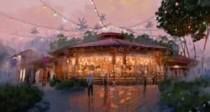 Guests stroll past a dazzling carousel illuminated at dusk, surrounded by twinkling string lights and lush palm trees—capturing the vibrant, celebratory atmosphere inspired by Tropical Americas’ newest attractions in Disney’s Animal Kingdom.
