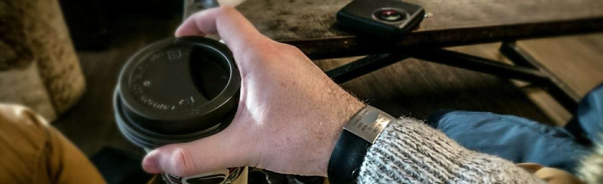 Person med et ID-armbånd, mens han holder en kaffekop. Hvorfor bære et ID-armbånd?