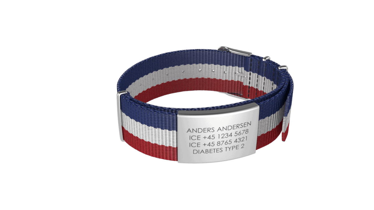 DJUVA Hit komplet armbånd: Gråt ID-armbånd med rød, hvid og blå stribet nylonrem, der viser personlig kontakt- og medicinske oplysninger.