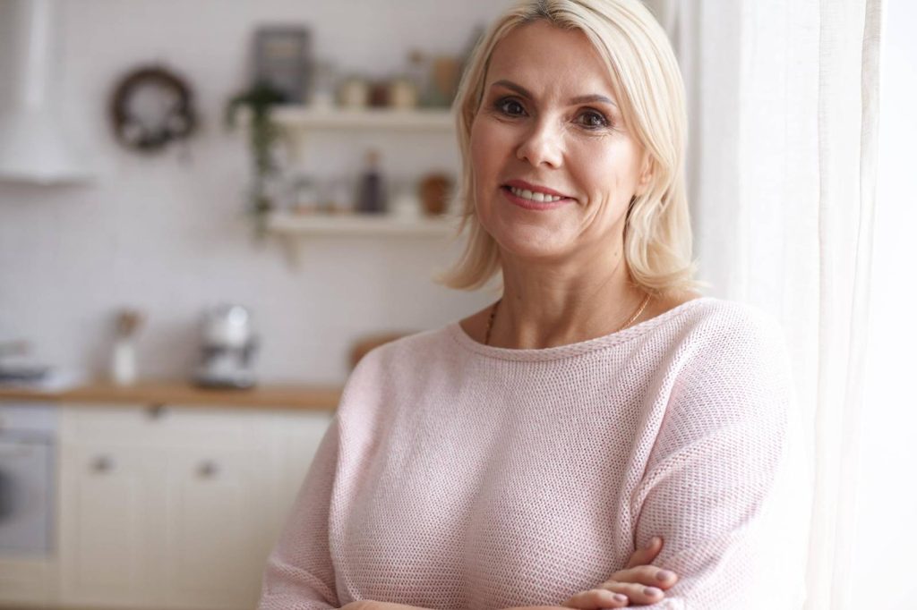 Naturalna kobieta uśmiechająca się w jasnym domu, idealna do artykułów o domu i ogrodzie.