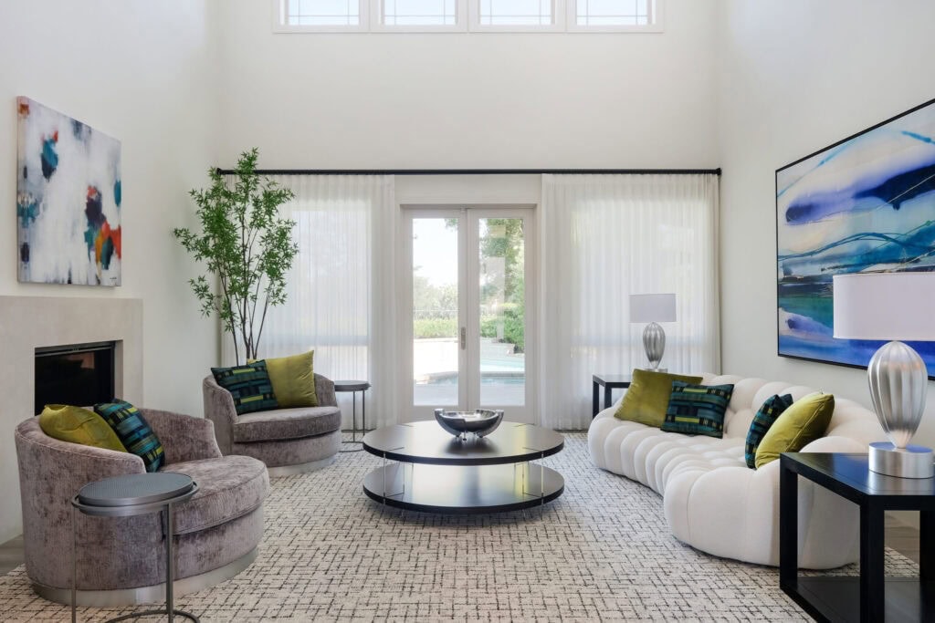 Modern living room with contemporary furniture and large windows showcasing outdoor pool view.