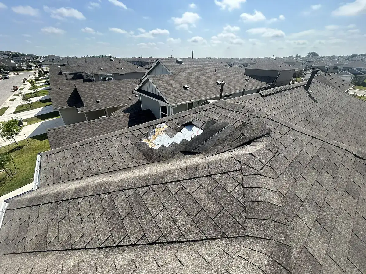Missing and damaged shingles exposing underlayment as clear signs of roof wind damage by Dolan Roofing & Construction