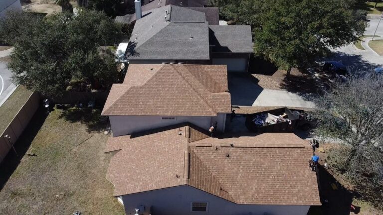 Aerial drone view of residential houses with new brown shingle roofs during a roofing replacement in Universal City TX by Dolan Roofing & Construction