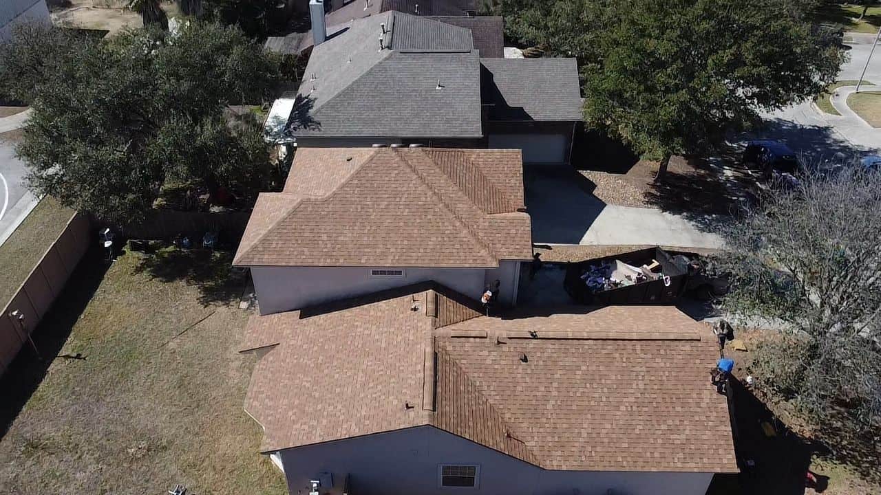 Aerial drone view of residential houses with new brown shingle roofs during a roofing replacement in Universal City TX by Dolan Roofing & Construction