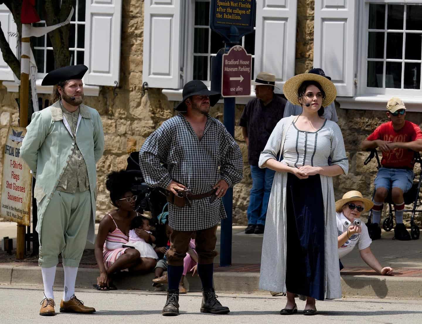 Reenactors dressed in colonial costumes perform in downtown Washington, Pennsylvania, showcasing ear.