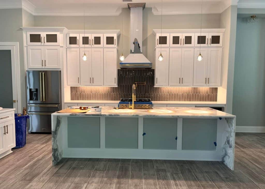 Custom white kitchen cabinetry with decorative range hood and island