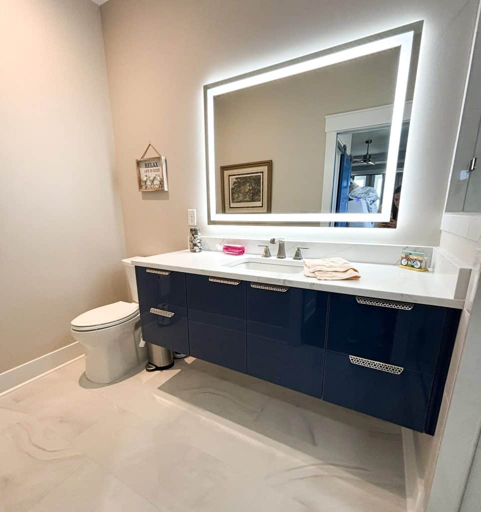 Floating master bathroom vanity with navy cabinetry and LED mirror