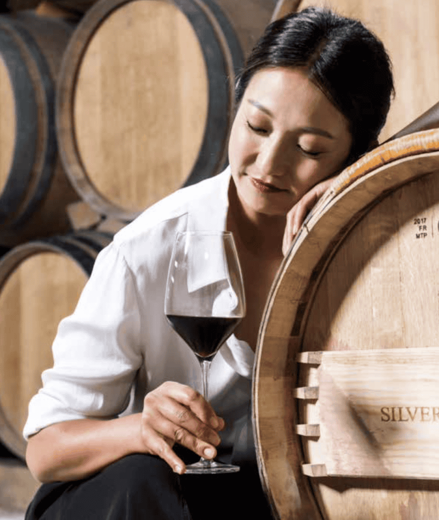 Woman with wine glass by wooden barrels