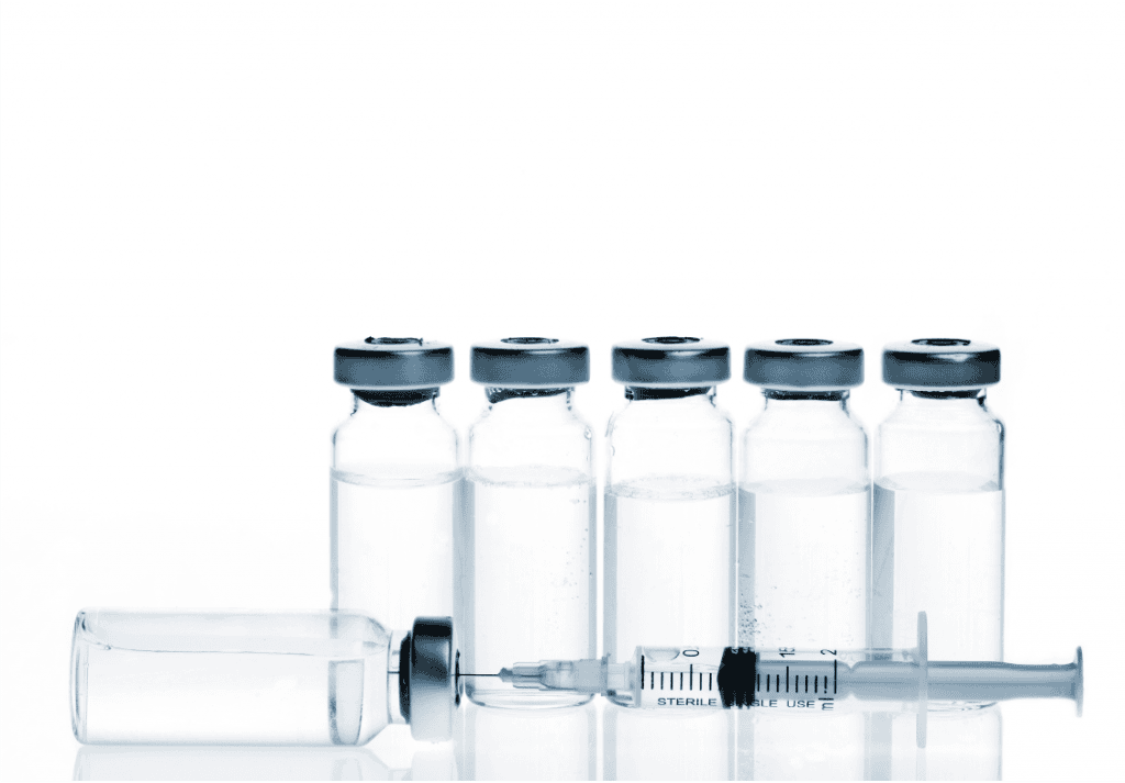 Vaccine vials and syringe on white background.