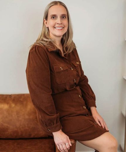 Woman sitting on a brown leather sofa.