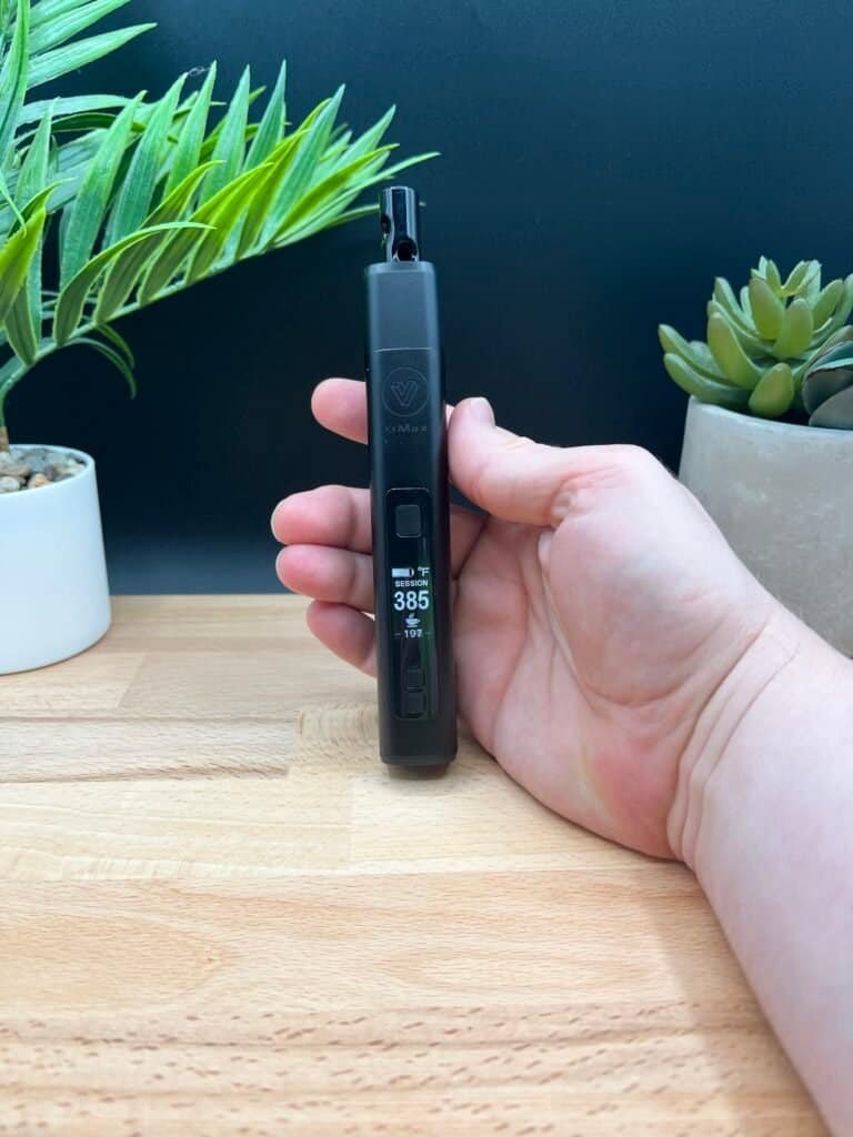 Here’s how you can optimize your image for SEO and engagement: SEO Alt Text (For Search Engines) "XMAX V3 Pro dry herb vaporizer held in hand, displaying 38.5W power settings with a sleek black design, set against a wooden surface and green plants. Ideal for showcasing vaping technology and aesthetics.