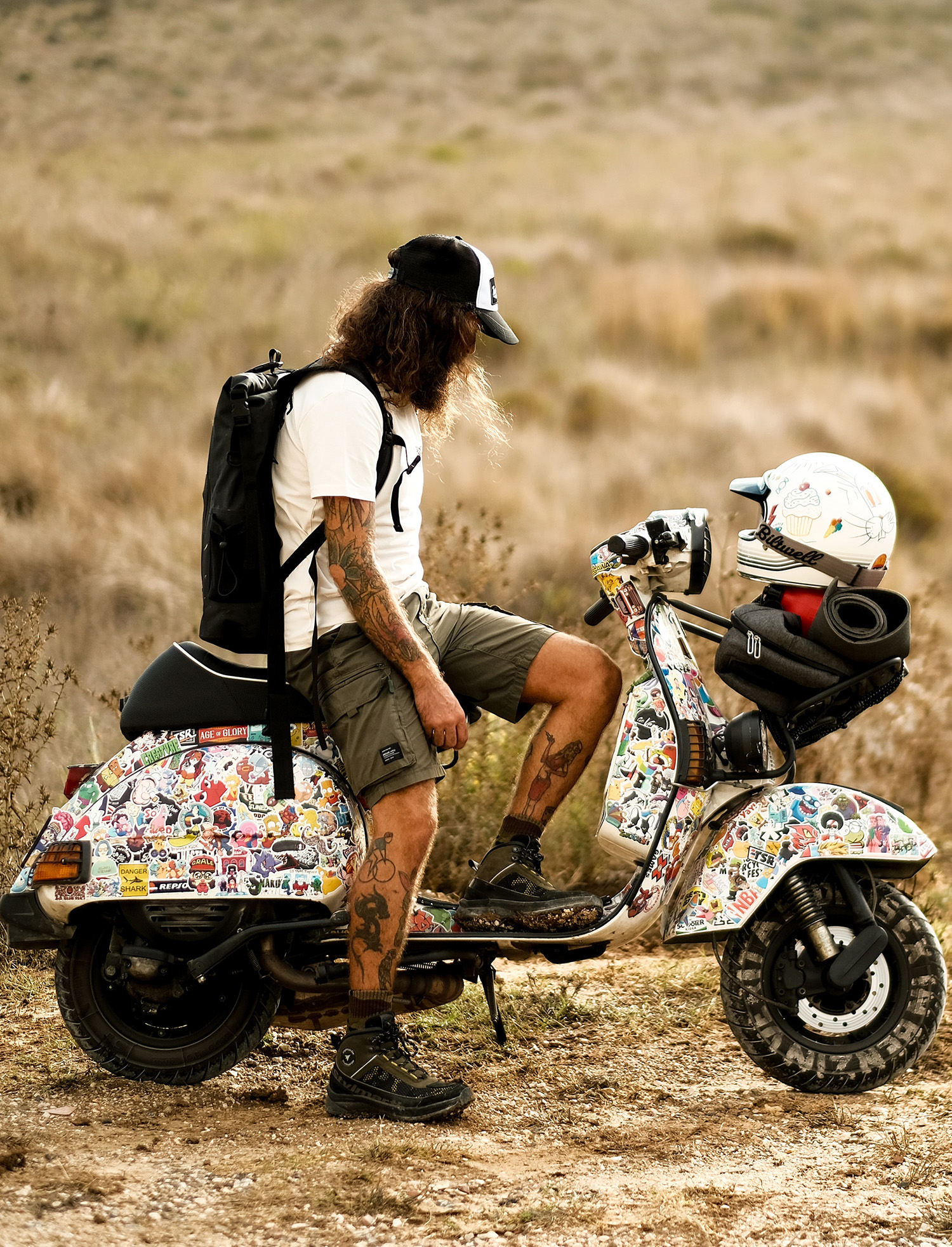 Waterproof backpack and gear on vintage scooter in outdoor setting.