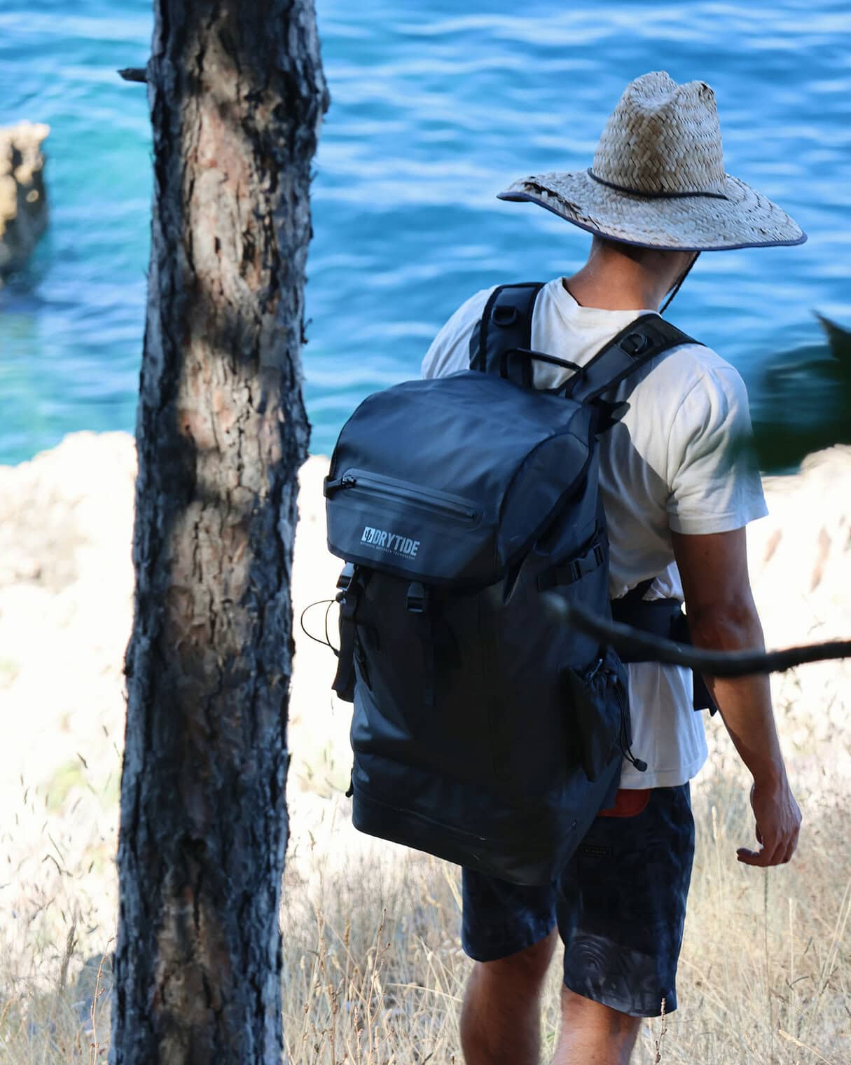 Person with a waterproof backpack near water, outdoor adventure gear.