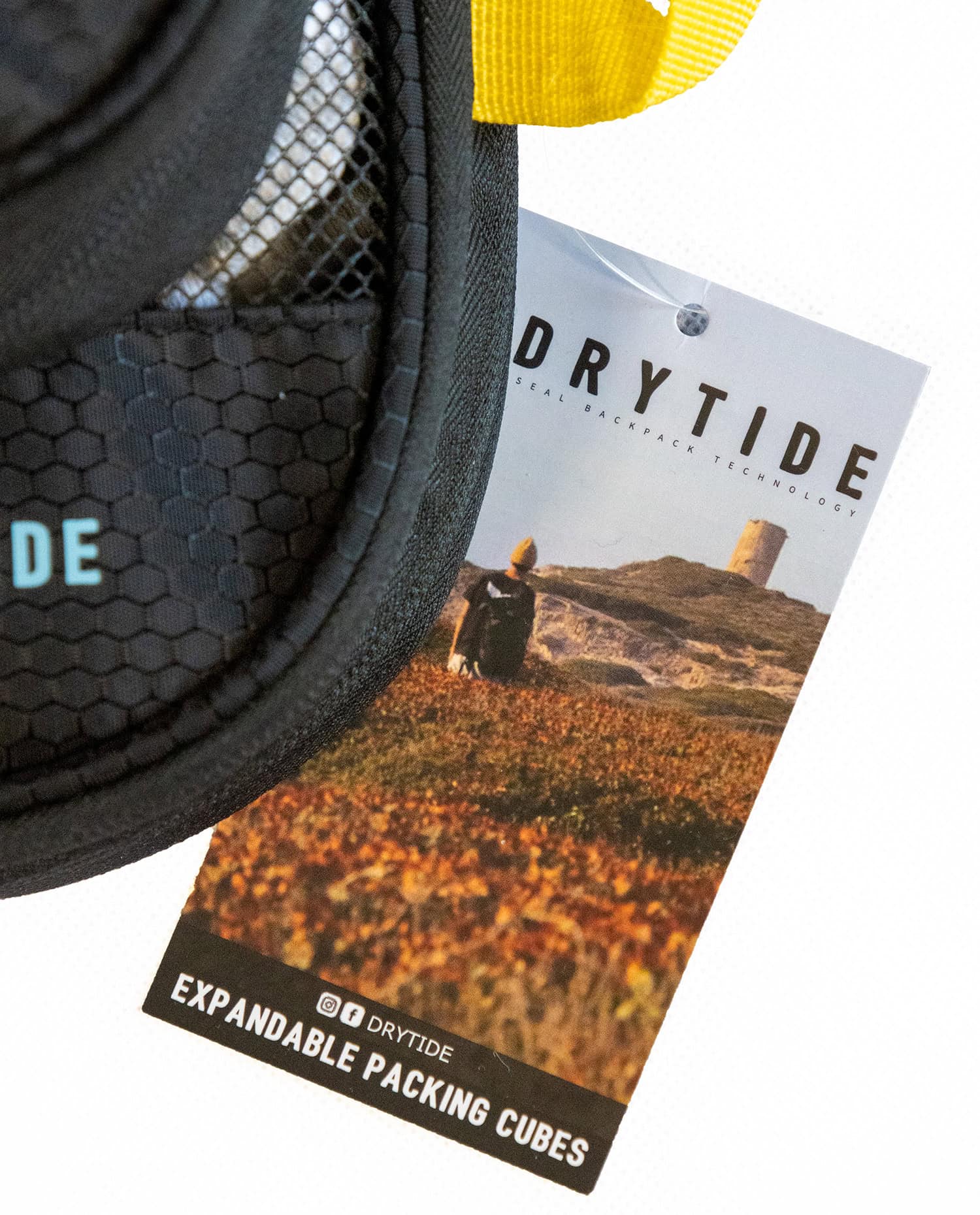 Waterproof gear tag attached to backpack with landscape background.