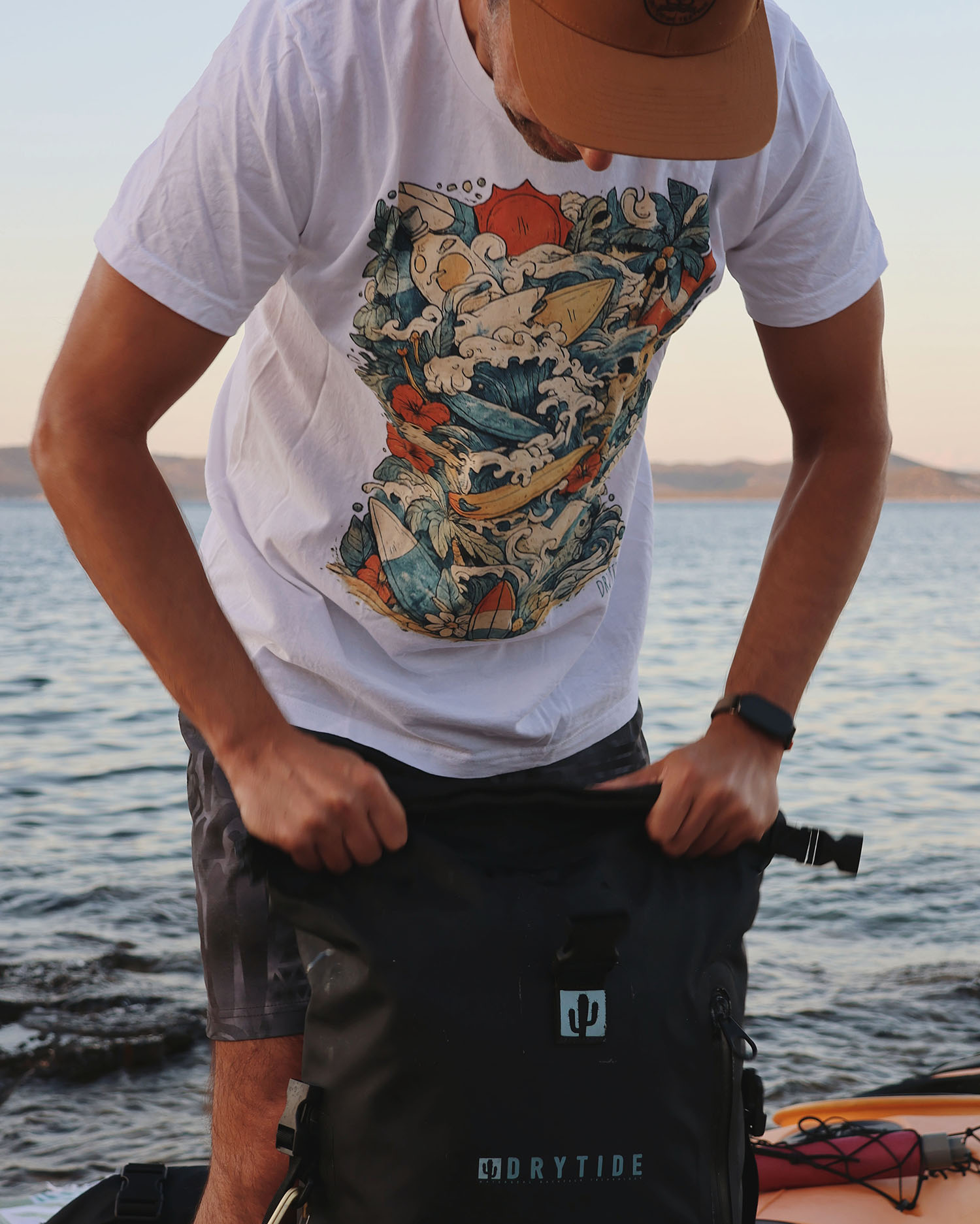 Jungle madness tee in color Drytide waterproof backpack being packed near water during outdoor activity.