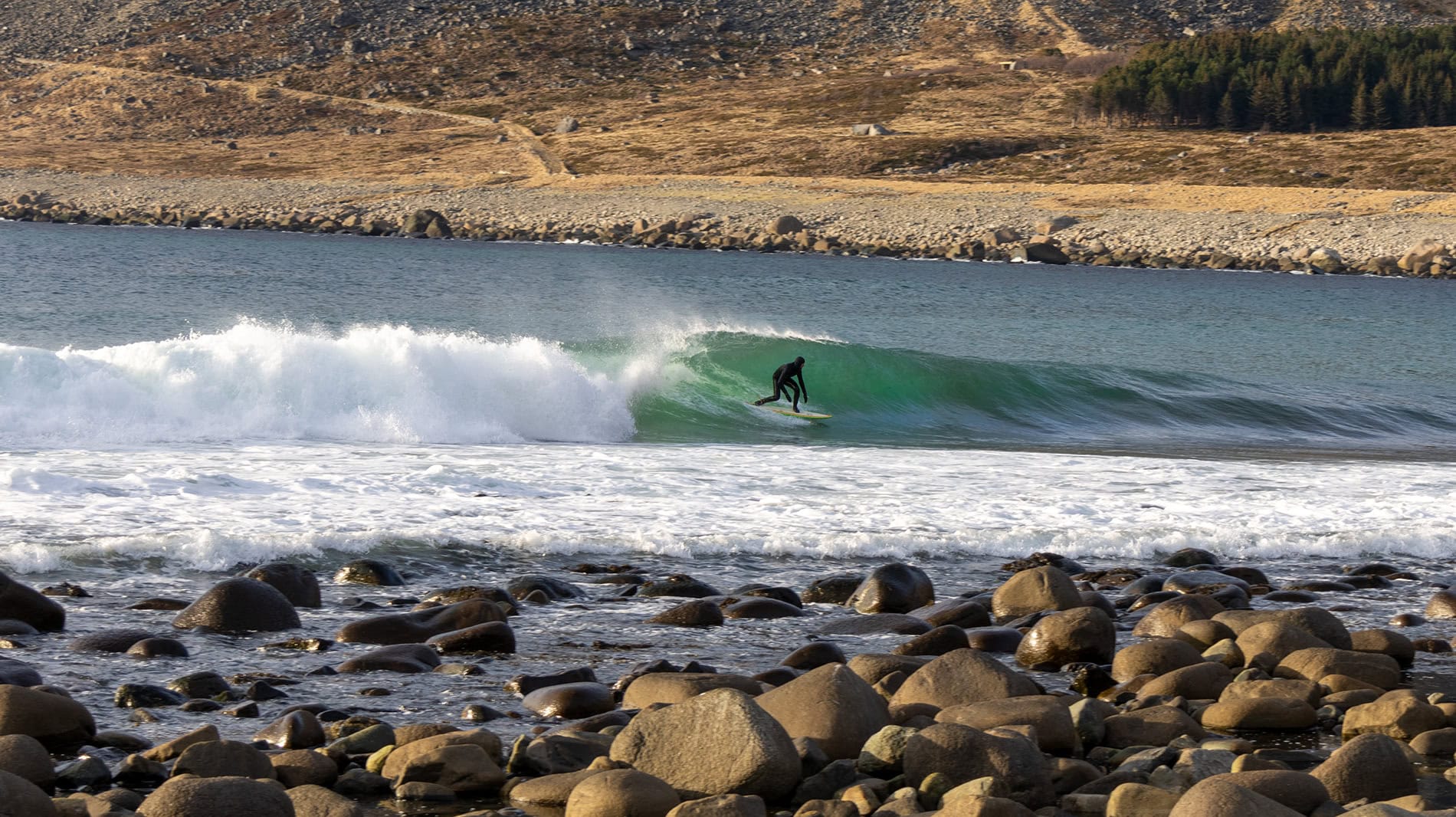 Surfer on a left at Unstad, Lofoten islands, Arctic circle