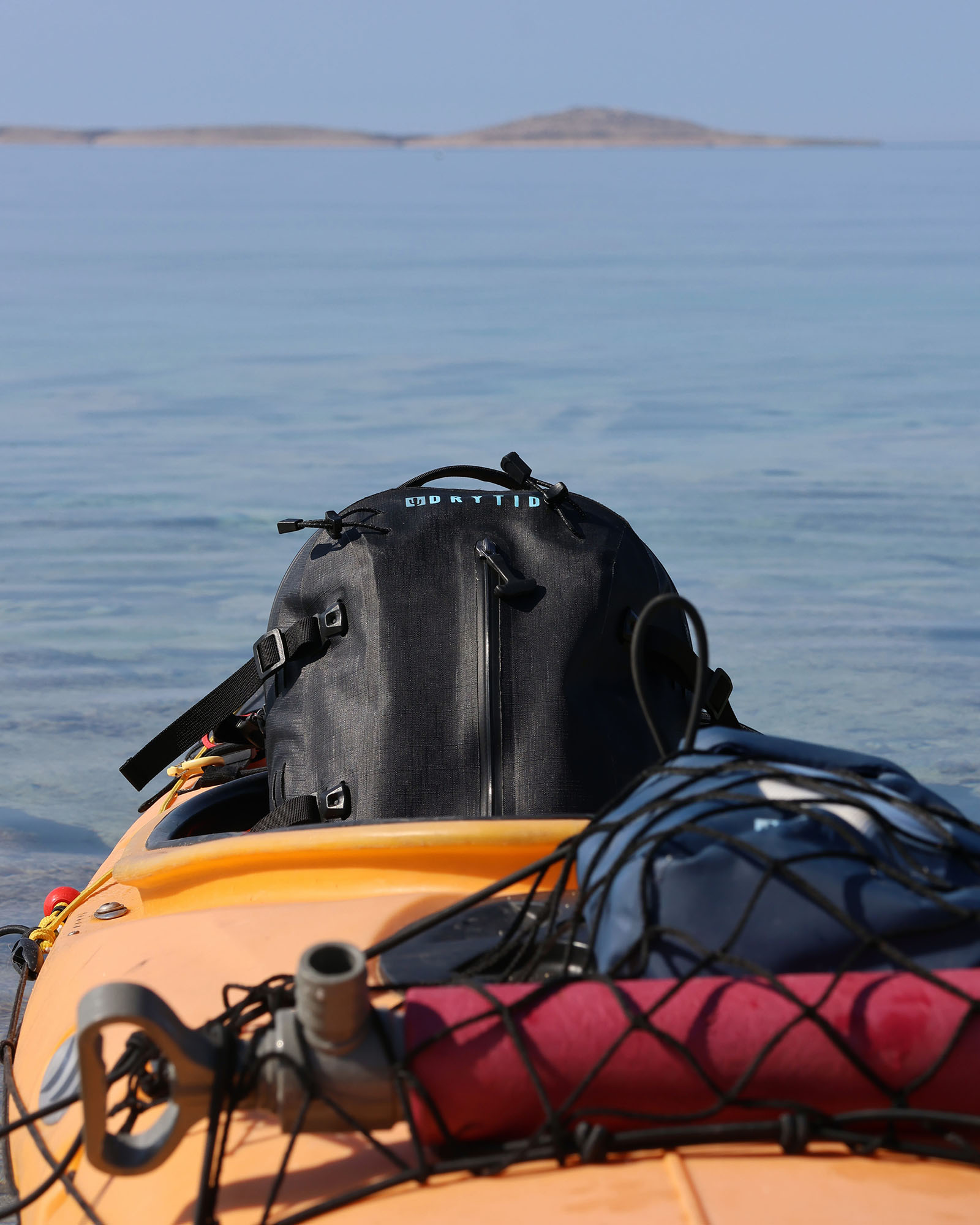 point nemo sea kayak journey DryTide waterproof backpack on kayak with water and distant island in background.