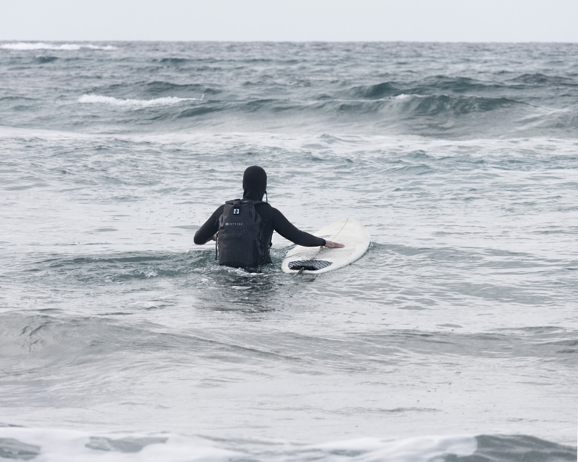 Person with waterproof backpack surfing in the ocean waves.