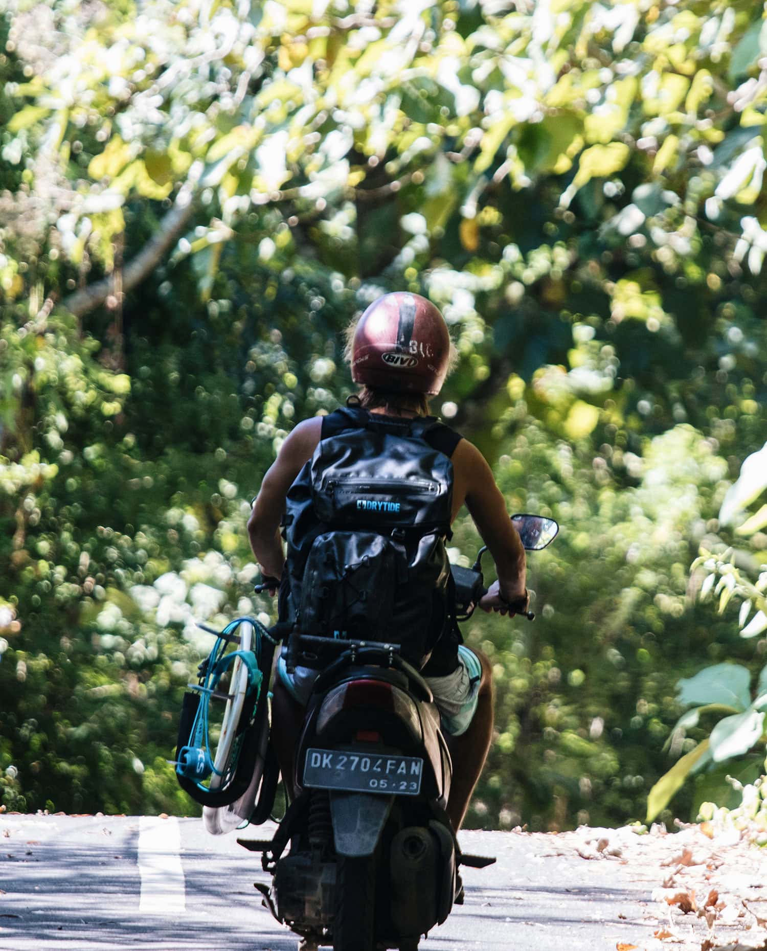 Waterproof backpack on cyclist in forest, ideal for outdoor travel and adventures.