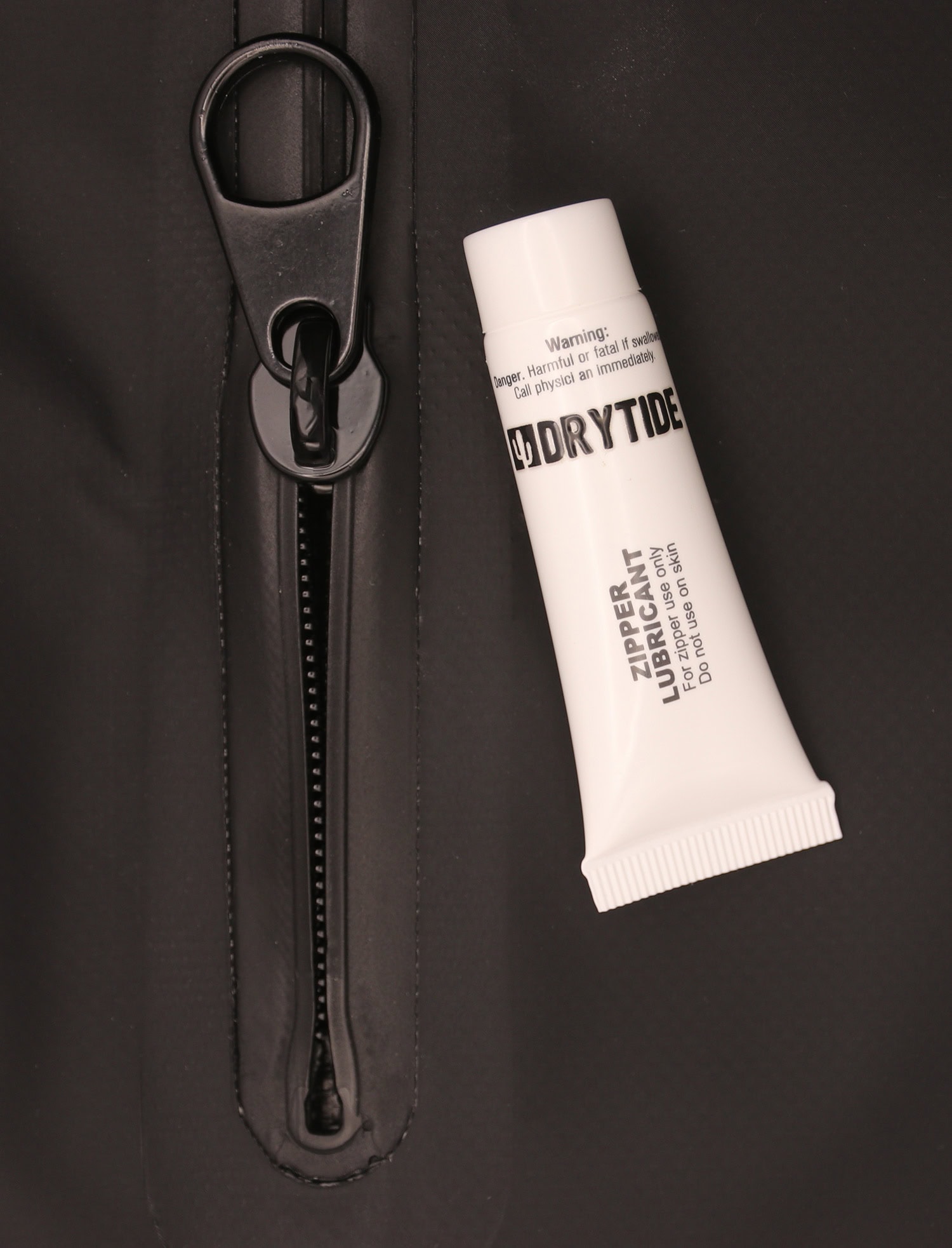 Close-up of Drytide zipper lubricant tube on waterproof jacket zipper.