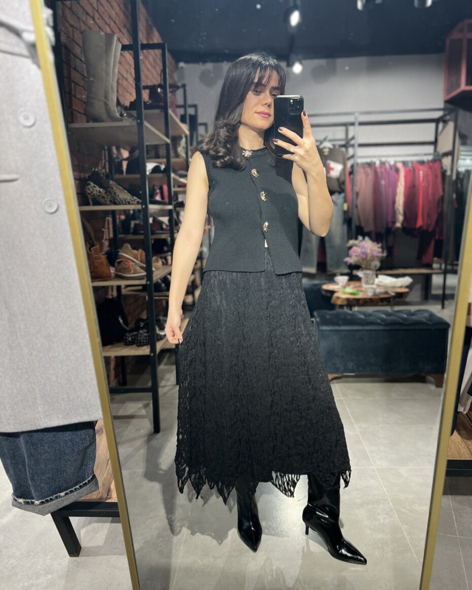 Düğmeli triko yelek ve şık etek kombini, kadın moda trendlerini yansıtan şık ve rahat bir görünüm.