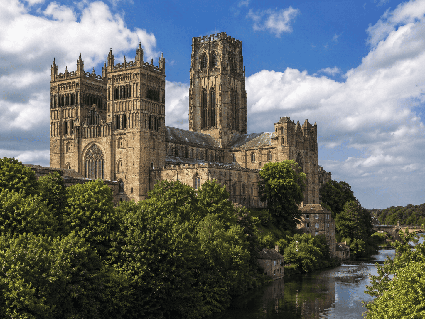 Photo realistic view of Durham Cathedral overlooking the River Wear with historic stone towers, green woodland and a blue sky.